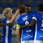 Spelers van KRC Genk vieren samen op het veld in blauwe wedstrijdtenues.