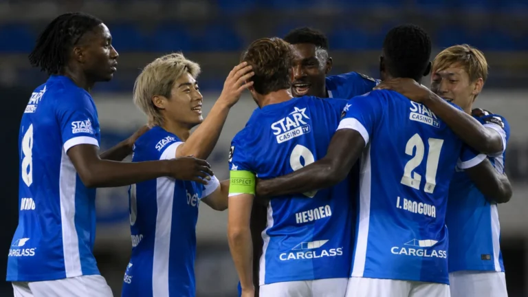 Spelers van KRC Genk vieren samen op het veld in blauwe wedstrijdtenues.