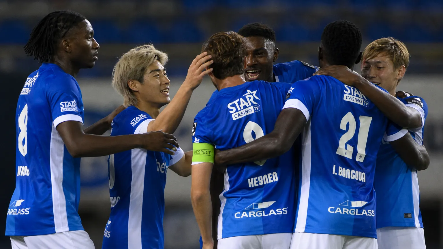 Spelers van KRC Genk vieren samen op het veld in blauwe wedstrijdtenues.