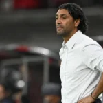 Een Antwerp-coach in een wit hemd observeert geconcentreerd langs de zijlijn.