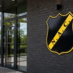 De lege ingang van het clubgebouw van NAC Breda met het vaste clubembleem aan de gevel.