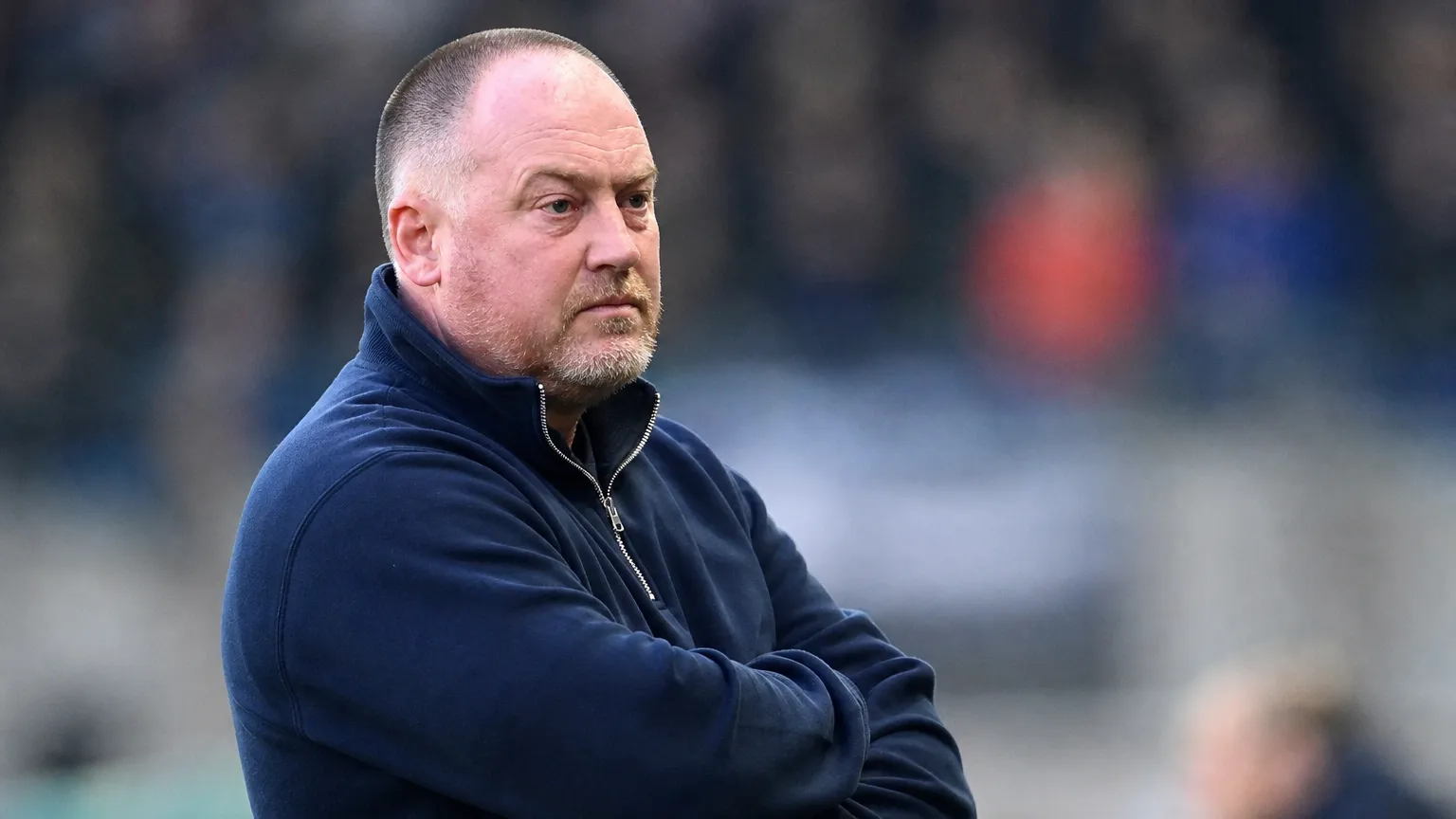 Fred Vanderbiest staat geconcentreerd langs de zijlijn van een voetbalveld.