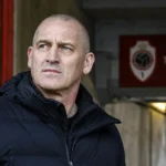Patrick Goots in een donkere jas bij de ingang onder Tribune 2 op de Bosuil.