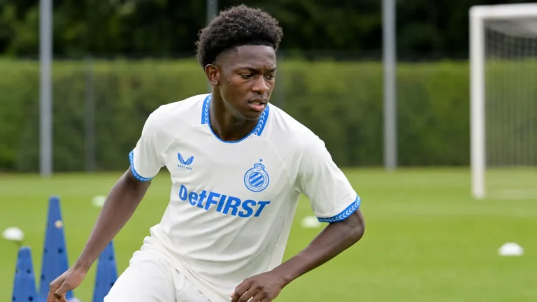 Een jonge speler in een wit shirt met blauwe details op een trainingsveld.