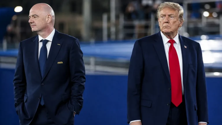 Twee mannen in donkere pakken bij een internationaal voetbalevenement.