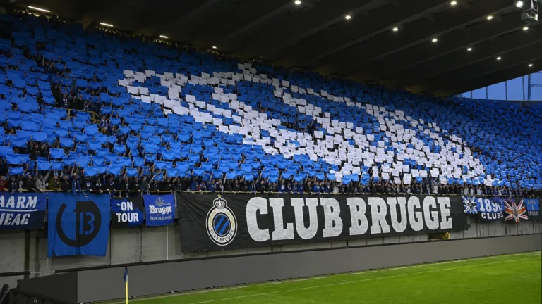 Collectieve Club Brugge-supporters op een overdekte tribune met een blauw-witte kaartenmozaïek.