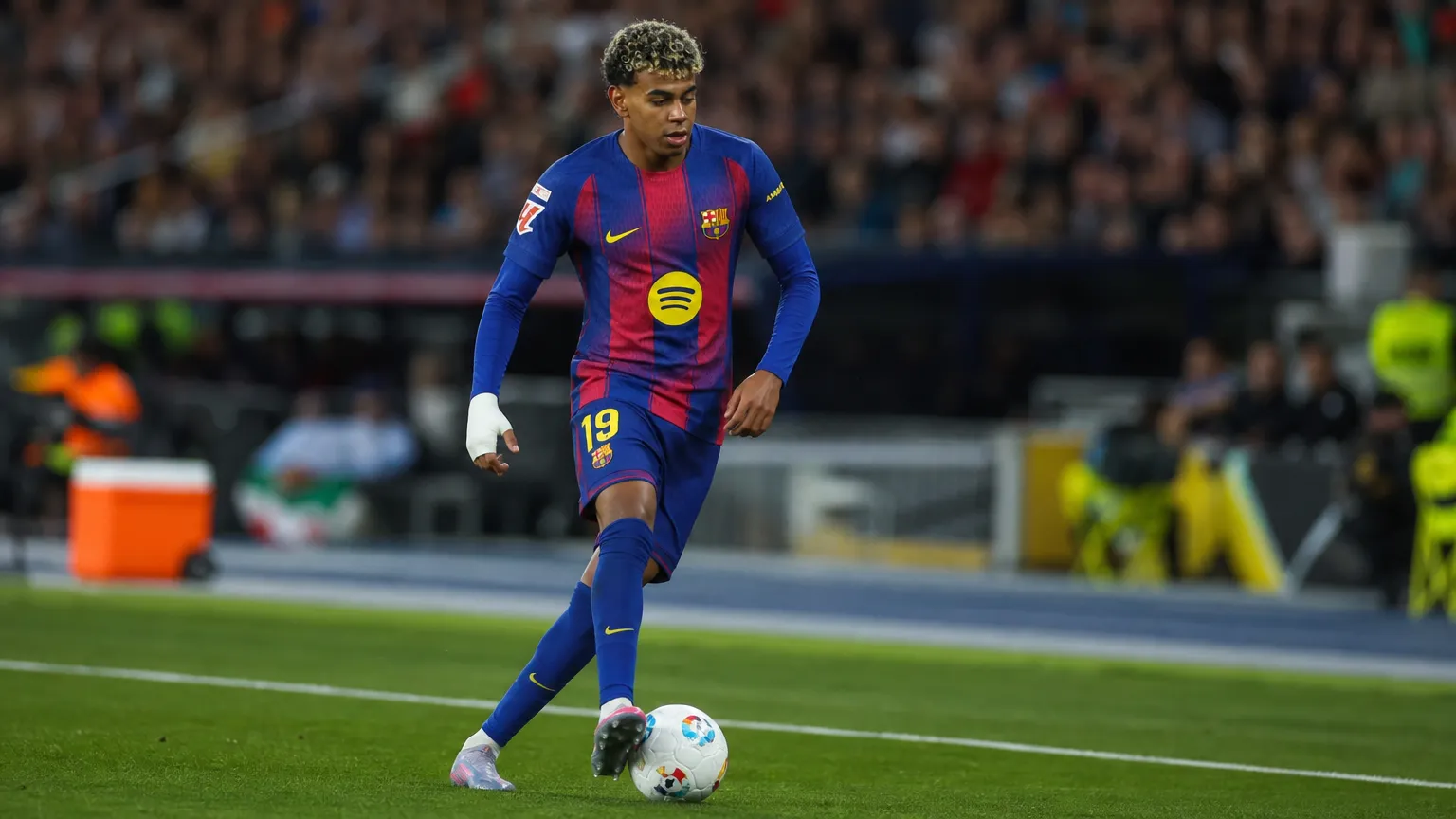 Een voetballer in een blauw-rood tenue tijdens een wedstrijdmoment.