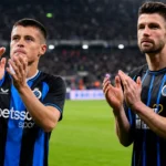 Twee Club Brugge-spelers applaudisseren op een Europees verlicht voetbalveld.