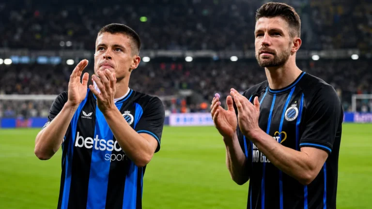 Twee Club Brugge-spelers applaudisseren op een Europees verlicht voetbalveld.
