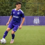 Enzo Sternal in het paarse tenue van RSCA Futures op een kunstgrasveld.