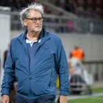 Jacky Mathijssen in een blauw sportjack in een voetbalstadion.