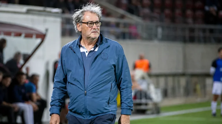 Jacky Mathijssen in een blauw sportjack in een voetbalstadion.