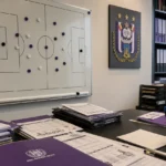Operationele kantoorruimte van RSC Anderlecht met een tactisch planbord en een clubembleem aan de wand.