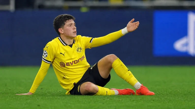 Konstantinos Karetsas zit op het gras in zijn gele wedstrijdtenue tijdens een Champions League-duel.