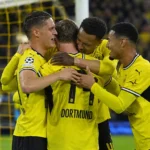Een groep Dortmund-spelers viert samen vlak voor het doel in een vol stadion.