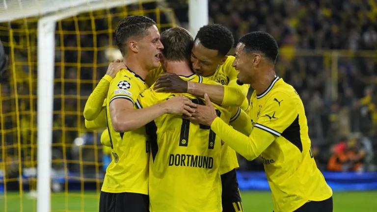 Een groep Dortmund-spelers viert samen vlak voor het doel in een vol stadion.