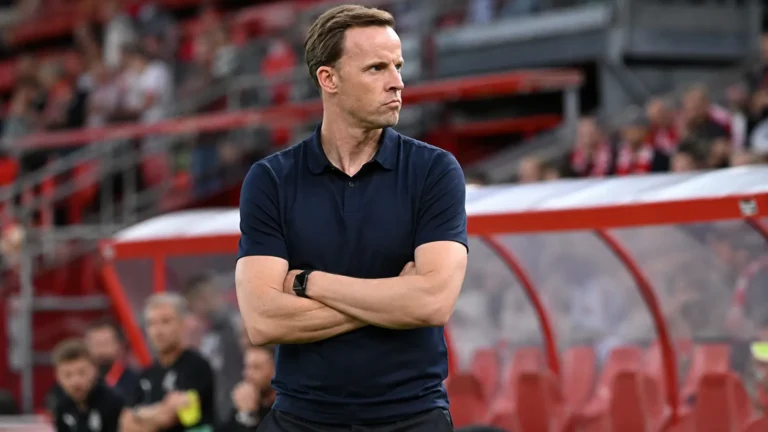 Een Standard-trainer volgt geconcentreerd de wedstrijd vanaf de zijlijn.