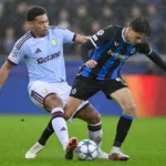 Een speler van Club Brugge in duel met een tegenstander tijdens een regenachtige wedstrijd.