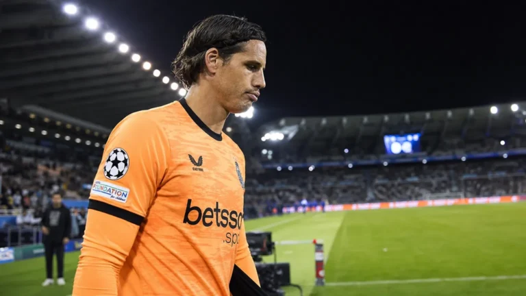 Een doelman in een oranje wedstrijdtenue wandelt na een Champions League-match over het veld.