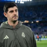 Thibaut Courtois in een donkere Real Madrid-jas aan de rand van het veld na een wedstrijd.