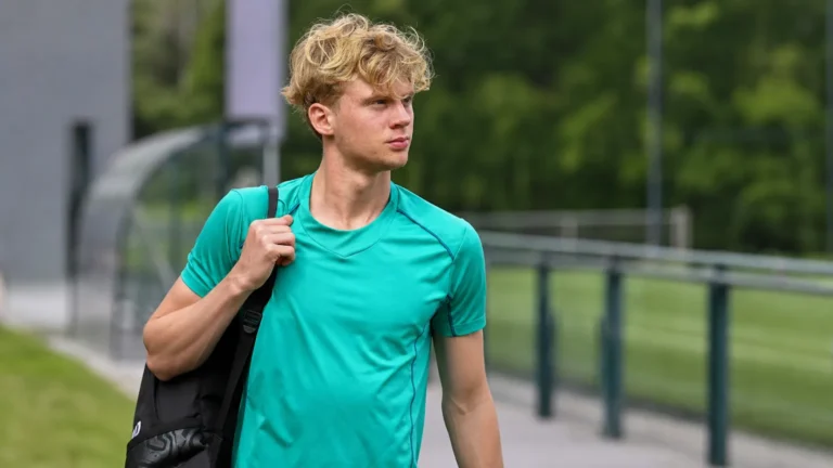 Cedric Hatenboer wandelt met een sporttas langs een trainingsveld.