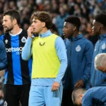 Een groep spelers en stafleden van Club Brugge langs de zijlijn van een stadion.