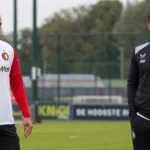 Een Feyenoord-speler en een staflid op het trainingsveld.