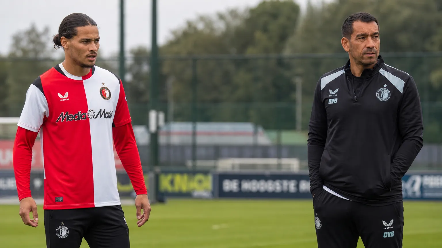 Een Feyenoord-speler en een staflid op het trainingsveld.