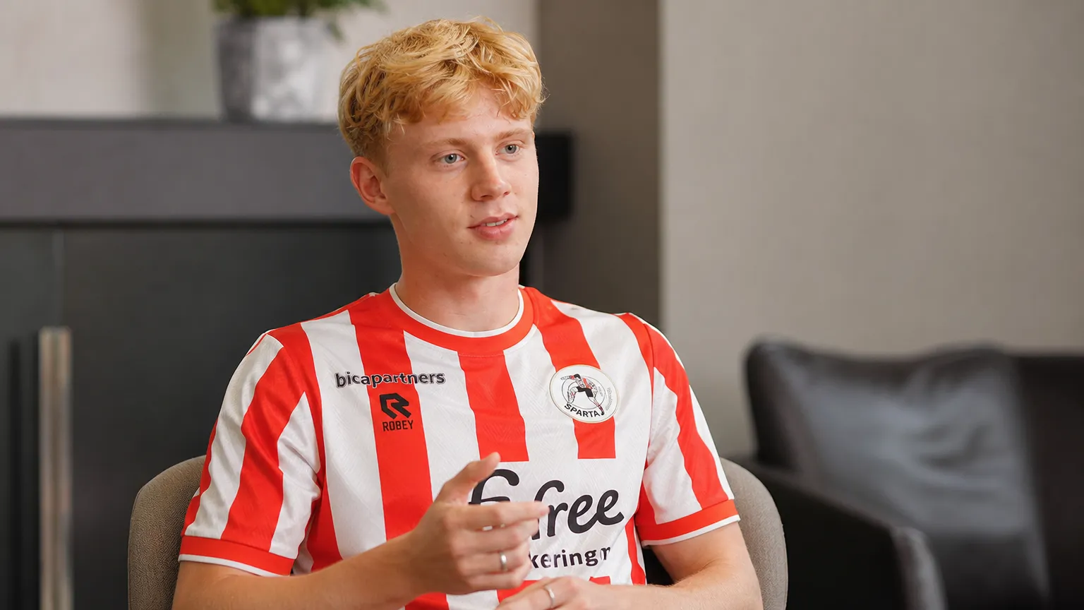 Cedric Hatenboer spreekt tijdens een voetbalinterview in een rood-wit gestreept shirt.
