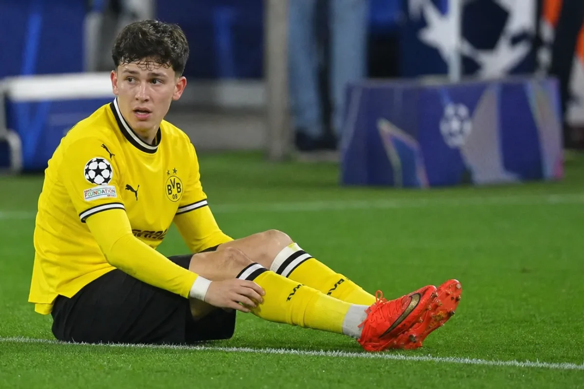 Konstantinos Karetsas zit op het gras in het gele wedstrijdtenue van Borussia Dortmund.