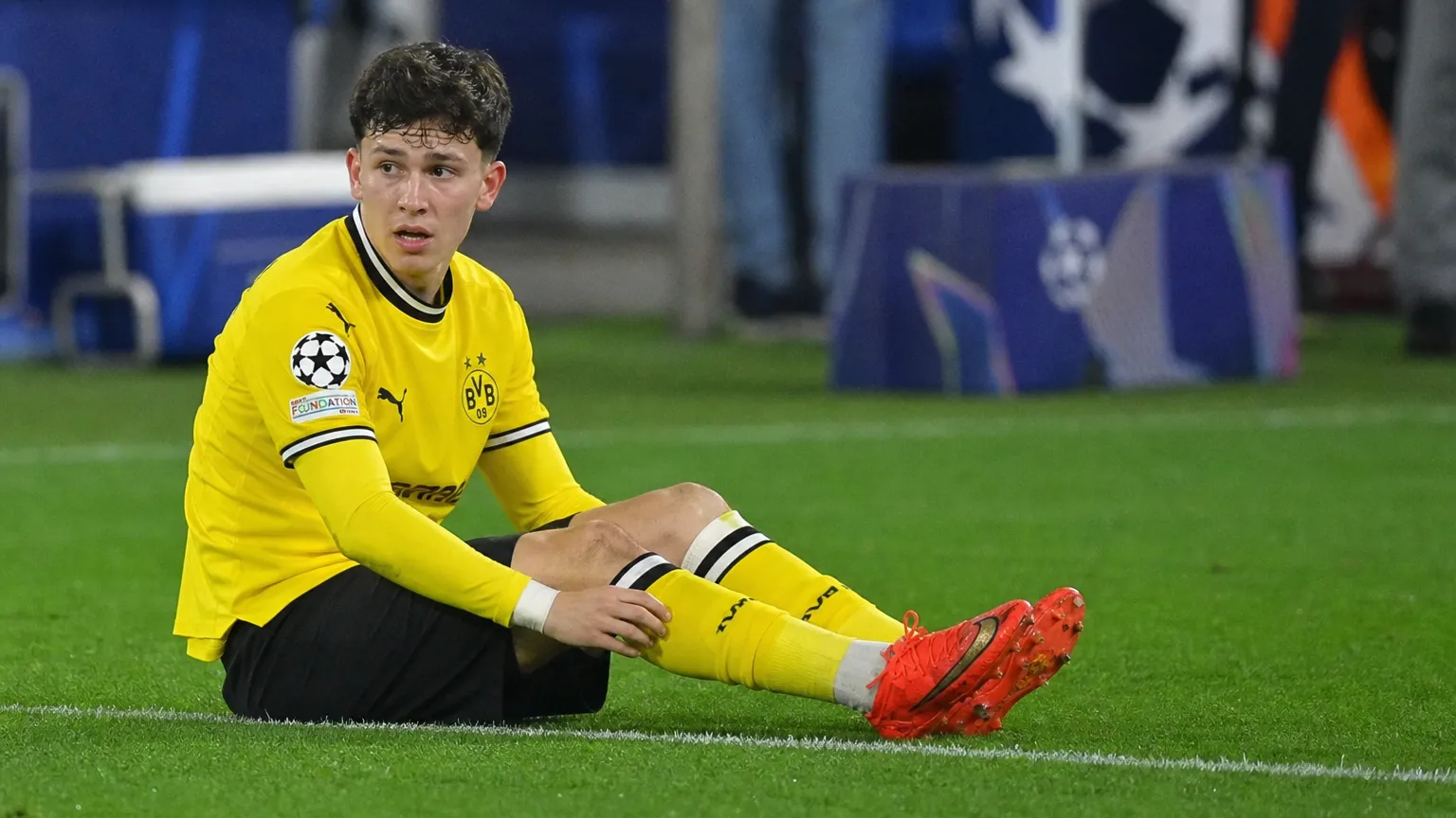 Konstantinos Karetsas zit op het gras in het gele wedstrijdtenue van Borussia Dortmund.