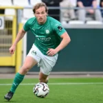 Een Lommel SK-speler in groen wedstrijdtenue tijdens een wedstrijdactie.