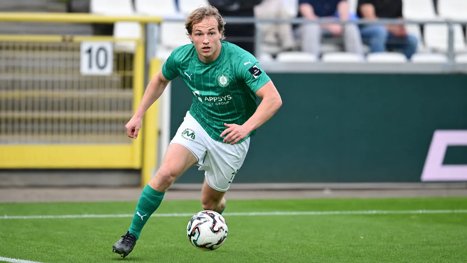 Een Lommel SK-speler in groen wedstrijdtenue tijdens een wedstrijdactie.