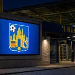Een verlicht aankondigingspaneel aan ’t Kuipje met het embleem van KVC Westerlo.