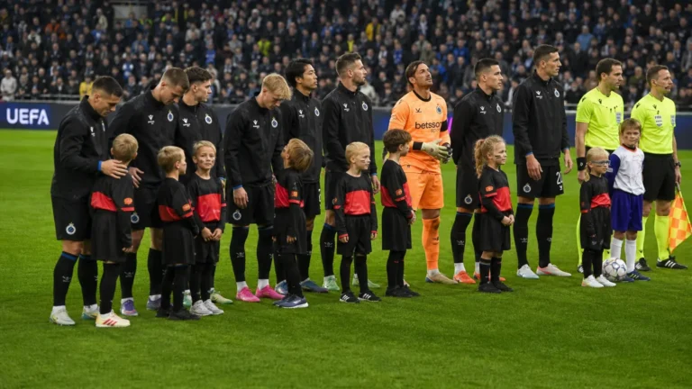 Een groep spelers van Club Brugge staat met mascottes en een scheidsrechter opgesteld op het veld.