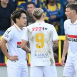Drie spelers van Westerlo in witte wedstrijdshirts die elkaar op het veld opzoeken.