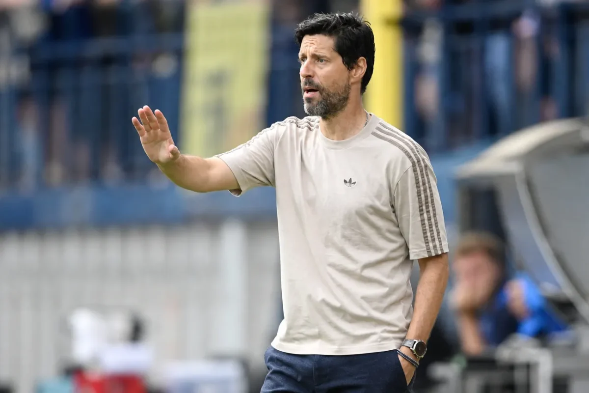 Een coach geeft aanwijzingen langs de zijlijn tijdens een voetbalwedstrijd.