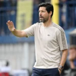 Een coach geeft aanwijzingen langs de zijlijn tijdens een voetbalwedstrijd.
