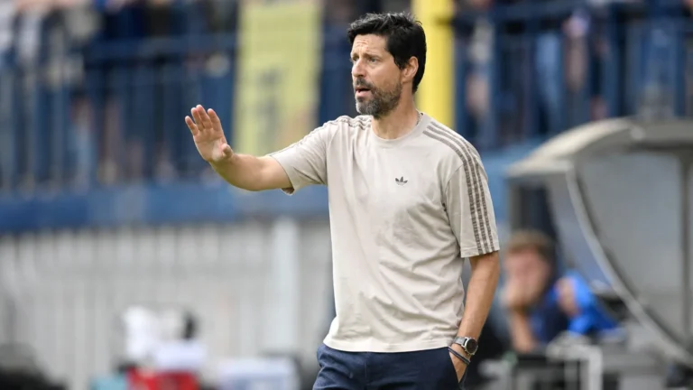 Een coach geeft aanwijzingen langs de zijlijn tijdens een voetbalwedstrijd.