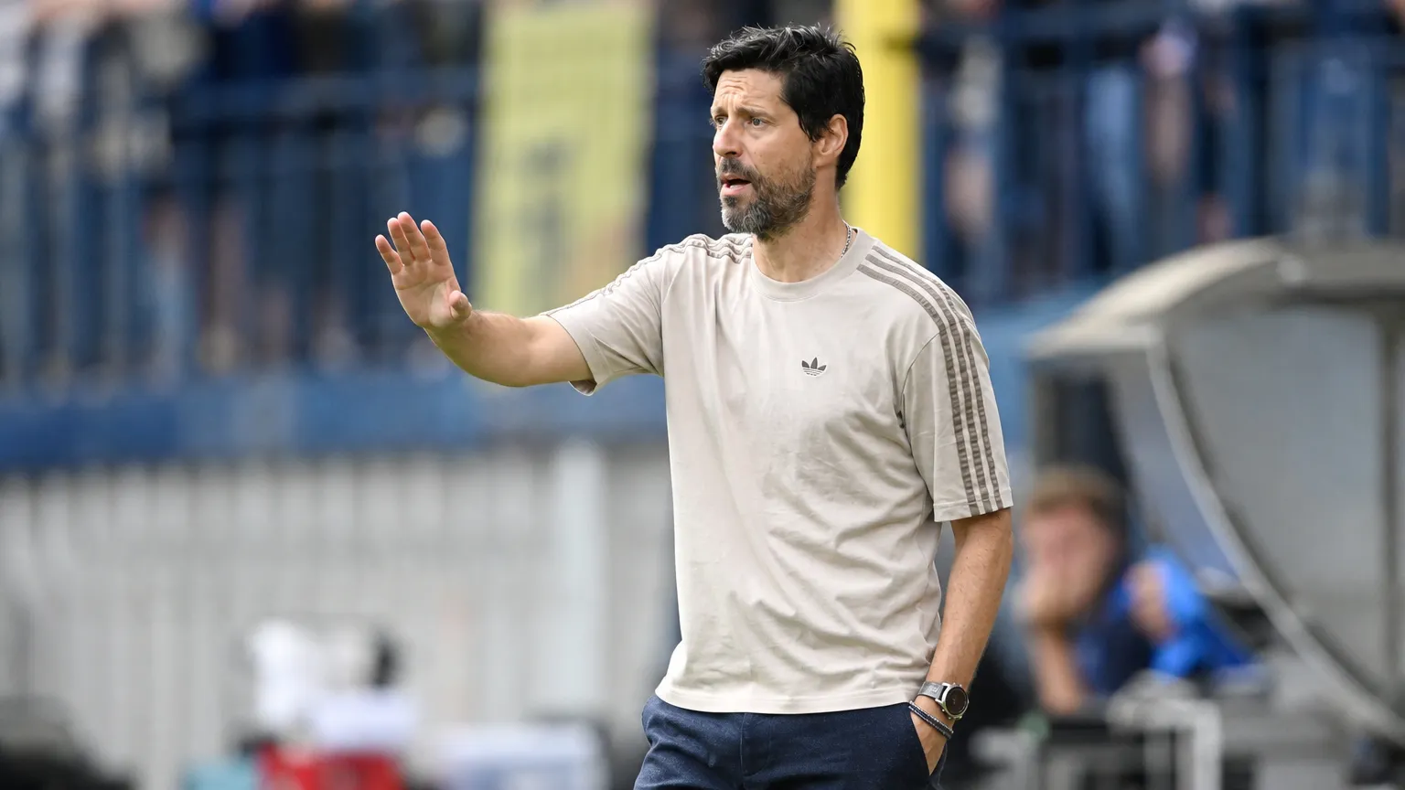 Een coach geeft aanwijzingen langs de zijlijn tijdens een voetbalwedstrijd.
