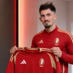 Andi Zeqiri poseert met een Standard-shirt tijdens zijn voorstelling in Luik.
