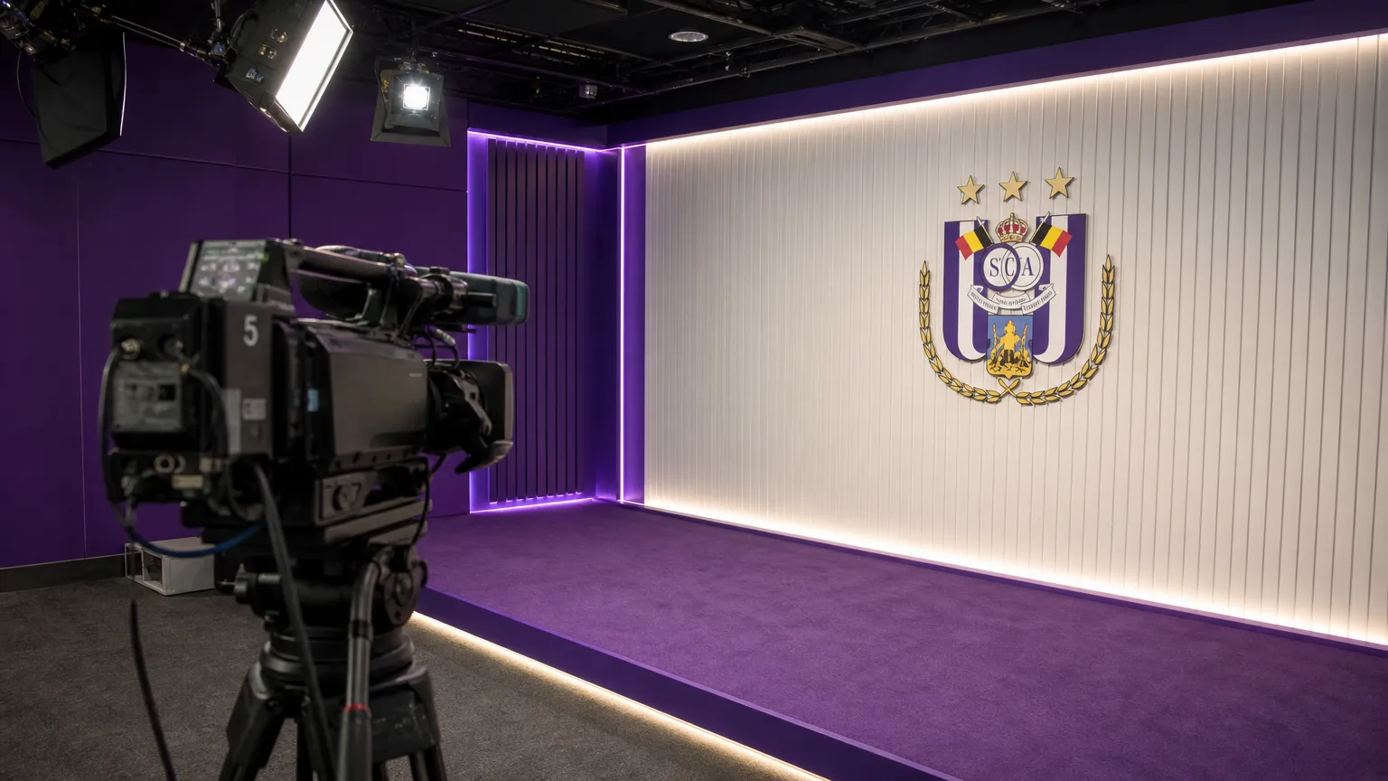 Een clubmedia-camera in een presentatiezone van RSC Anderlecht met één embleem aan de wand.