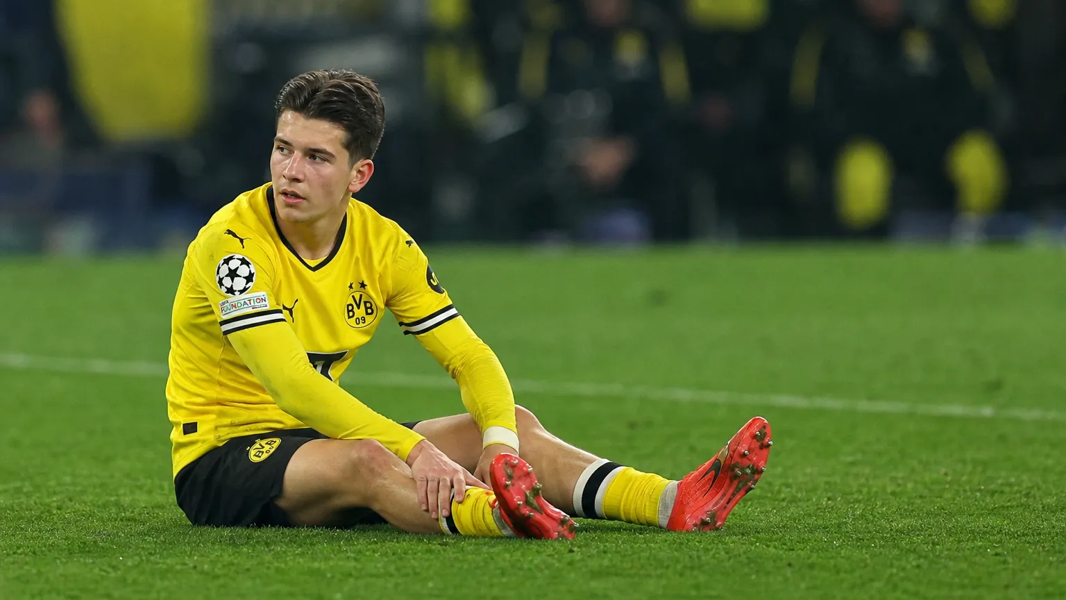 Kos Karetsas van Borussia Dortmund zit op het veld tijdens een medische onderbreking.