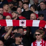 Een collectieve groep Antwerp-supporters met rood-witte sjaals op de tribune.