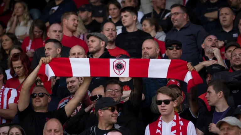 Een collectieve groep Antwerp-supporters met rood-witte sjaals op de tribune.