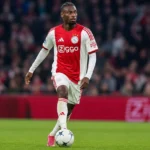 Jorthy Mokio controleert de bal op het middenveld in een Ajax-tenue.