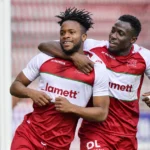 Twee spelers van Zulte Waregem vieren een doelpunt nabij het doel.