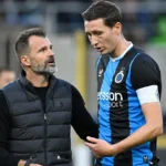Een coach en een Club Brugge-speler overleggen langs de zijlijn.