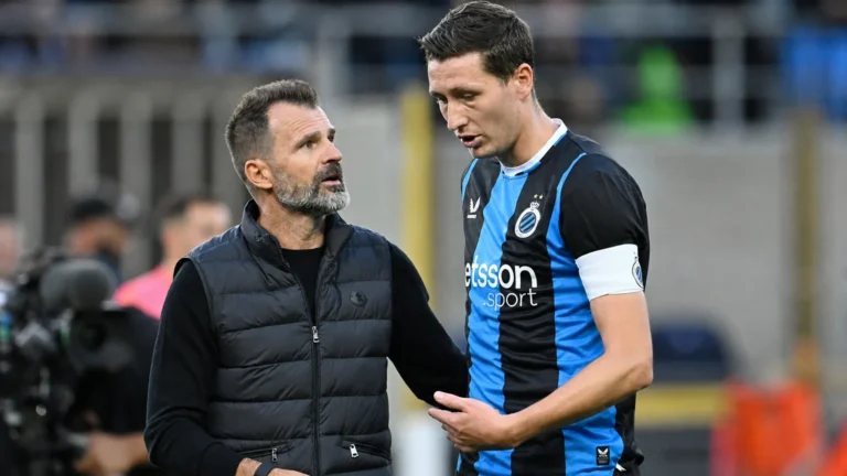 Een coach en een Club Brugge-speler overleggen langs de zijlijn.