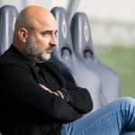 Een clubofficial van Anderlecht zit geconcentreerd op de bank langs het veld.